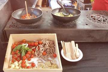 Making pasta with tomatoes and ravioli in a street cafe on a Sunny day. City fast food
