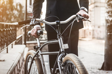 My bicycle gets me to work everyday. Cropped shot of  man rolling his bicycle on the way to work.