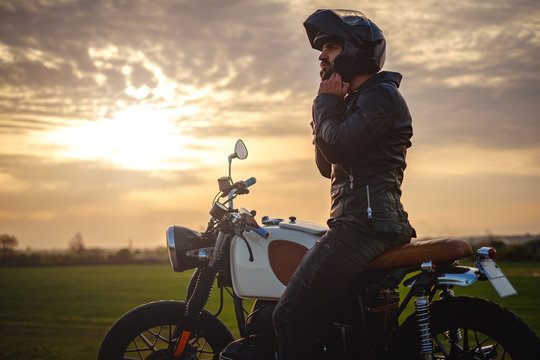 Biker Sitting On Motorcycle And Putting On His Helmet