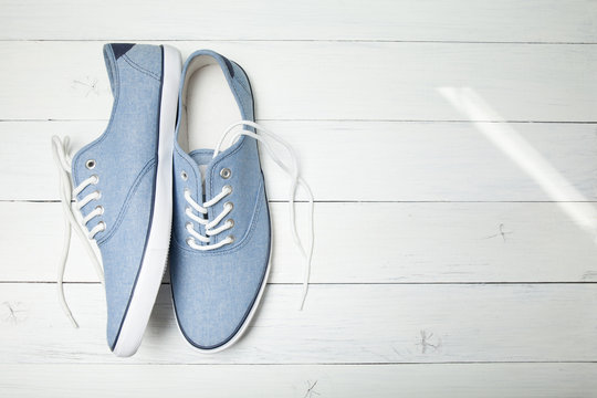 Summer casual sneakers on a white wooden background. Copy space for text.