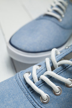 Fashionable casual blue sneakers with white laces on a blue background.