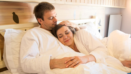 Portrait of beautiful young couple lying in bed and embracing