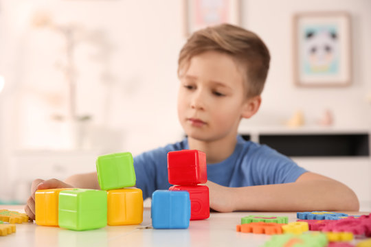 Little boy with autistic disorder playing at home, closeup of cubes
