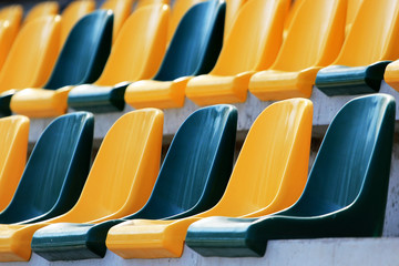 Rows of plastic yellow and green seats at a stadium