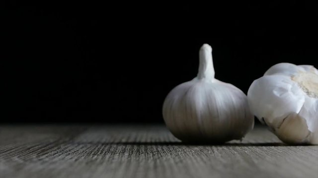 Slow motion Garlic falling on wooden table againts black background
