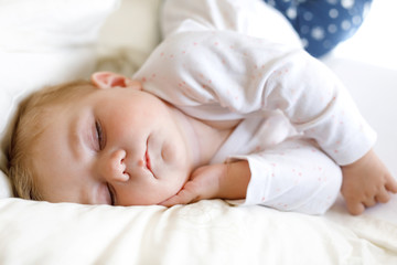 Cute adorable baby girl of 6 months sleeping peaceful in bed