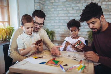 Two fathers play educational games with their children, having fun.