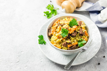 Moroccan spicy pilaf in a bowl on light concrete background. Selective focus, space for text. 