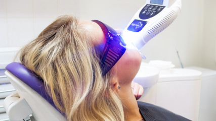 Closeup portrait of young female patient during teeth whitening procedure