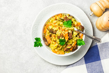 Curried rice pilaf in a bowl on light concrete background. Top view, copy space.