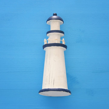 vacation and summer image with lighthouse over blue wooden background.