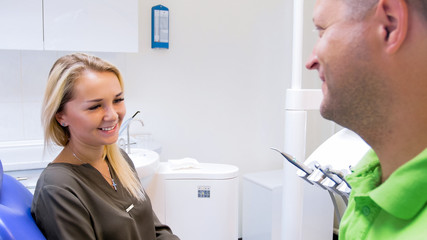 Obraz premium Closeup portrait of beautiful young owman smiling to her dentist after treatment