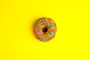 Donut glazed with sprinkles on a yellow background. Modern flat lay photo pattern in pop art style,...