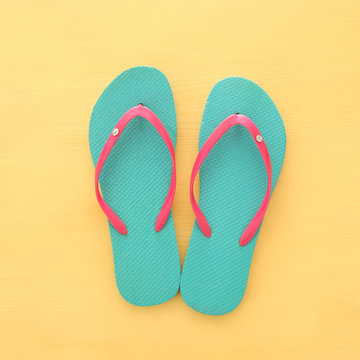 vacation and summer image with flipflops over yellow wooden background.