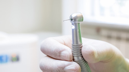 Macro image of dentist hand in latex glove holding dental drill