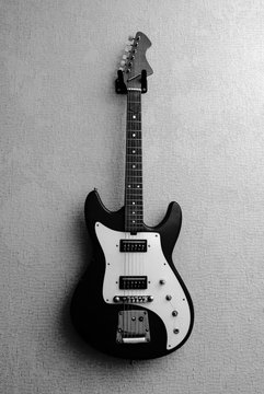 Black and white picture of old vintage electric guitar hanging on the wall