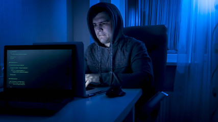 Portrait of frustrated young programmer working on laptop at home