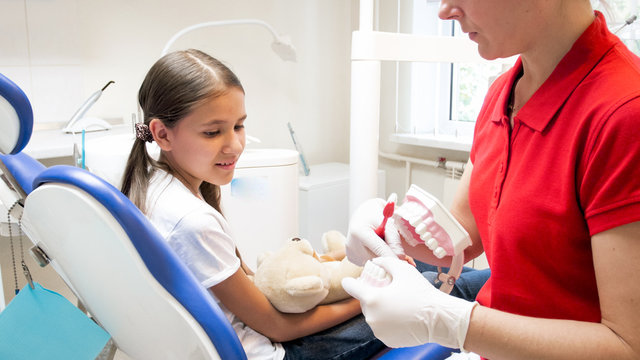 Closeup image of pediatric dentist teaching girl about tooth hygiene
