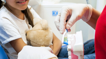 Closeup image of pediatric dentist using totthbrush and plastic teeth model