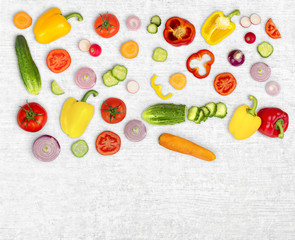 Vegetable mix on white wooden isolated background. Fresh yellow pepper, chopped tomatoes, onion, round cucumber slice, carrot, radish. The concept of a healthy lifestyle. Vegetarian food.