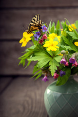 butterfly and bouquet of field wild flowers in a vase on old boards
