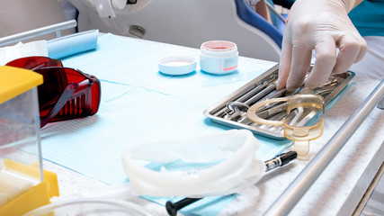 Closeup image of doctors hand taking special metal instruments from tray