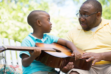 Father teaaching his his son to play the guitar.