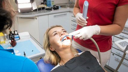 Closeup image of dentist assistant removing saliva from patients mouth with special sucking tube