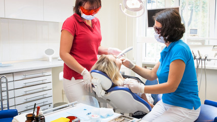 Dentist treating patients teeth with dental curing UV lamp