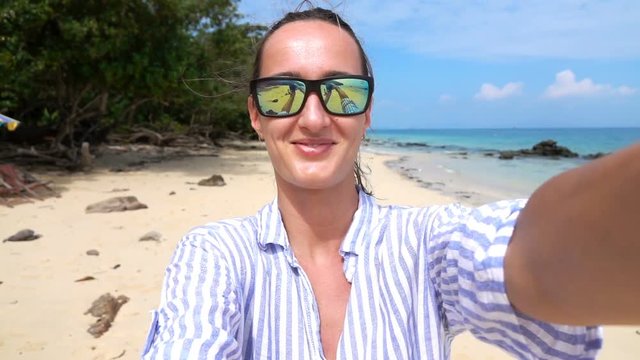 Young, happy woman recording selfie video walking on beach, slow motion
