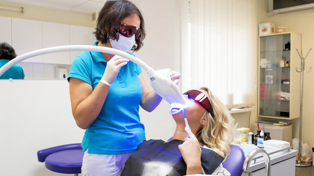 Female dentist adjusting UV light lamp for dental curing