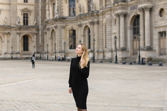 Female person in black dress standing near Louvre. Concept of visiting France and historic buildings.