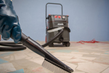 Man Vacuuming a Construction Site. Closeup of a cleaner in special clothes and rubber gloves holds...