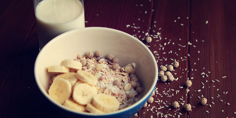 Healthy breakfast. Granola bowl with banana, raisins and nuts. And a glass of milk on the wooden background. Close up photo. Sweet vegan dish. Morning oatmeal closeup.