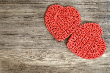 Two red knitted hearts on old natural wood. The concept for Valentine's Day or background for a greeting card. Top view. Copy space.