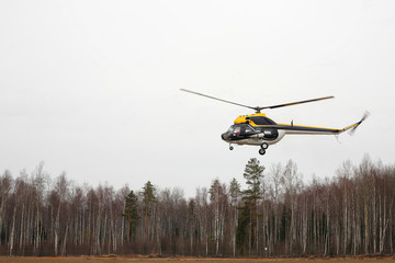 Aircraft - Black-yellow helicopter makes flight low height side view