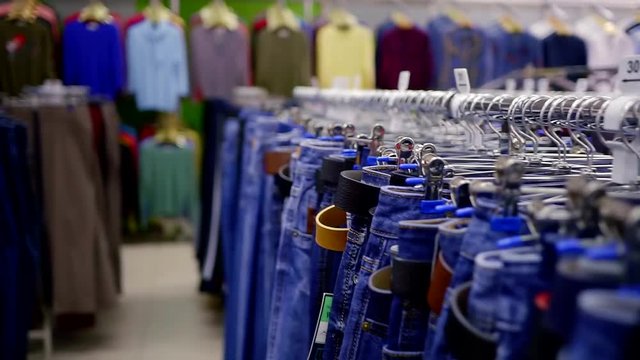 close shot at the rows with clothes, a lot of various jeans in the boutique on the hangers