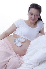 Kobieta w ciąży a na brzuszku małe buciki 