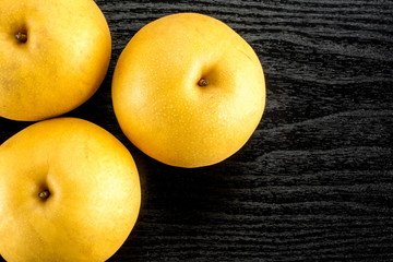 Chinese golden pears top view Nashi variety isolated on black wooden background three whole round.
