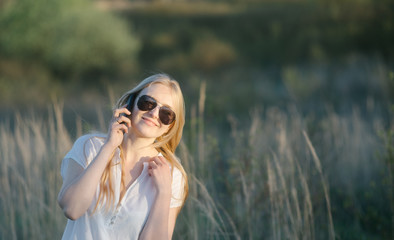 holding dress, boho beautiful blond woman in white dress in national park talking on the phone