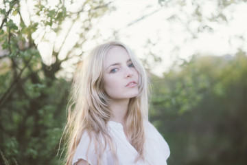 Naklejka premium beautiful blond woman in white dress in national park. holding dress, boho