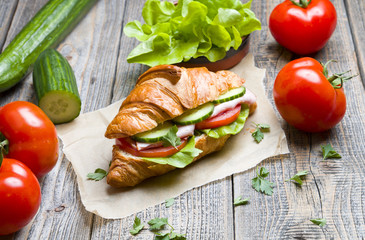 Croissant sandwich with fresh tomatoes cucumber and ham