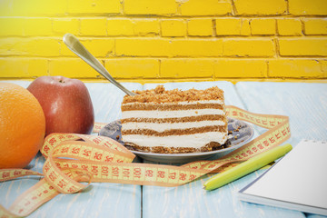 healthy food concept, piece of cake on wooden table and measuring tape with Notepad and pen.