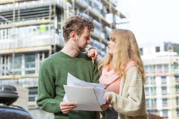 Couple with blueprint project keys on construction site
