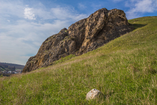 Rock in the mountains with green grass and blue cloudy sky in summer sunny day