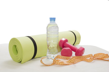Dumbbells,yoga mat, bottle of water and measuring tape for fitness and healthy lifestyle concept.