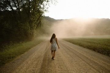 Woman Walking Down A Dusty Dirt Road in the Country