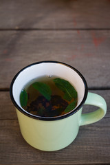 tea with mint in a green mug on a wooden background
