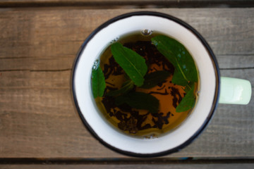 tea with mint in a green mug on a wooden background