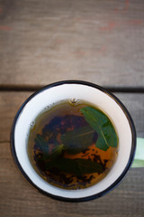 tea with mint in a green mug on a wooden background